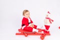 Child in Santa costume on red sleigh on white isolated background, new year and Christmas concept, place for text Royalty Free Stock Photo