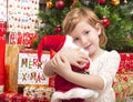 Child with santa doll in front of christmas tree