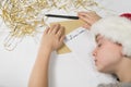 Child in Santa hat is sleeping at the table. Letter for Santa. Wooden background Royalty Free Stock Photo