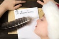 Child in Santa hat is sleeping at the table. Letter for Santa. Wooden background Royalty Free Stock Photo