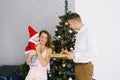 Child in a Santa suit in his mother`s arms near the Christmas tree, dad gives mom and baby a new year gift. The kid looks at his Royalty Free Stock Photo