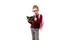 Child with schoolbag. Girl in white shirt and gray pants, rounded glasses, hold a book, school bag and posing like model Royalty Free Stock Photo