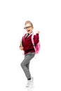 Child with schoolbag. Girl in white shirt and gray pants, rounded glasses, hold a book, school bag and posing like model Royalty Free Stock Photo