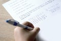 child, schoolchild hesitantly solves difficult task of adding numbers, writes down numbers, makes mistakes in notebook with pen,