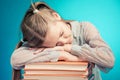 Child schoolgirl read Schoolgirl fell sleep on a stack of books. ing a book on blue background