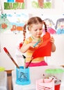 Child with scissors cut paper in playroom.