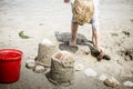 Child on Beach Builds Sand Castles with a Red Bucket. Royalty Free Stock Photo