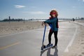 Child on scooter in park. Super hero child in a red superhero coat. Super hero concept. Royalty Free Stock Photo