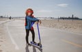 Child on scooter in park. Super hero child in a red superhero coat. Super hero concept. Royalty Free Stock Photo