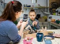 Mom photographs her daughter on a smartphone during a ceramics workshop Royalty Free Stock Photo