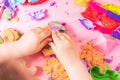 The child sculpts figures from multi-colored kinetic sand, developing fine motor skills of hands