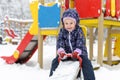 Child on seesaw in winter, little kid having fun on snowy playground