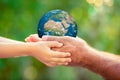 Child and senior holding Earth planet in hands