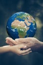 Child and senior holding Earth planet in hands