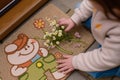 child setting a small daisy bunch on a cartooncharacter door mat