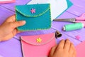 Child sewed a purse of felt. Small child holds a bright felt purse in his hands. Craft supplies, felt diy on a wooden table Royalty Free Stock Photo