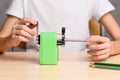 A child sharpens pencils with a mechanical sharpener