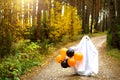 A child in sheets with slits like a ghost costume in an autumn forest with orange and black balls scares. Halloween Party