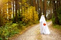 A child in sheets with slits like a ghost costume in an autumn forest scares and terrifies. A kind little ghost. Halloween Party