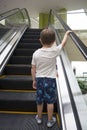 Child in shopping center standing on moving escalator. Royalty Free Stock Photo