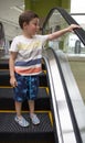 Child in shopping center standing on moving escalator Royalty Free Stock Photo