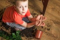 Child showing at dirty soil hands sitting on the floor with a broken pot of flowerpot Royalty Free Stock Photo