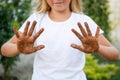 The child shows his hands in the dirt