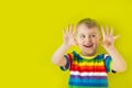 A joyful, cheerful, smiling child stretched out his palms forward. Green background.