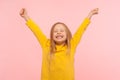 Child sincerely rejoicing success. Cute energetic enthusiastic little girl raising arms in excitement