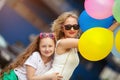 Child and sister in trendy sunglasses having fun outdoors with lots of colorful balloons