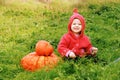 Child sit turn the floor on grass near huge pumpkin. Sunny warm day. copy space for text. The symbol and carnival costume of holid