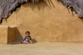 Child sits and crawls in front of the house made with mud and thatch in Khuri village,Jaisalmer,India Royalty Free Stock Photo