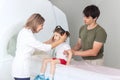 The child sits on a drawer of an MRI machine. Nearby A father and a female doctor are preparing a little girl for Royalty Free Stock Photo