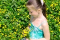 The child sits on a glade and holds flowers