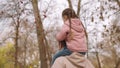 child sits his father& x27;s neck, dad carries kid on his shoulders in an autumn park, happy family, baby rides beloved Royalty Free Stock Photo