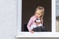 The child sits at low tide in the window in his hands a toy. Look at us. Dangerous situation Royalty Free Stock Photo