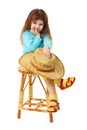 Child sits on an old wooden chair with hat