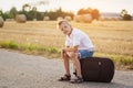 The child sits on a suitcase in the summer sunny day, the travel