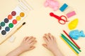 The child sits at the table with objects for creativity, drawing and hobbies, the top view. Royalty Free Stock Photo