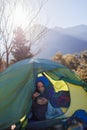 child sits in a tent against the backdrop of the mountains and has breakfast. boy in a sleeping bag with a plate in his hands. Royalty Free Stock Photo