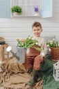 Child sits on veranda of country house watering can and bouquet of flowers tulips rubber boots nature spring family time Royalty Free Stock Photo