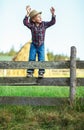 Little boy sits on wooden fence against picturesque haystack Royalty Free Stock Photo