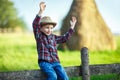 Little boy sits on wooden fence against picturesque haystack Royalty Free Stock Photo