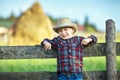 Little boy sits on wooden fence against picturesque haystack Royalty Free Stock Photo