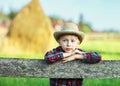 Little boy sits on wooden fence against picturesque haystack Royalty Free Stock Photo