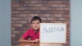 Child sitting at the desk holding flipchart with lettering freed