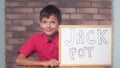 Child sitting at the desk holding flipchart with lettering jackp