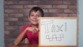 Child sitting at the desk holding flipchart with lettering taxi