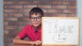Child sitting at the desk holding flipchart with lettering time