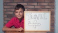 Child sitting at the desk holding flipchart with lettering trave Royalty Free Stock Photo